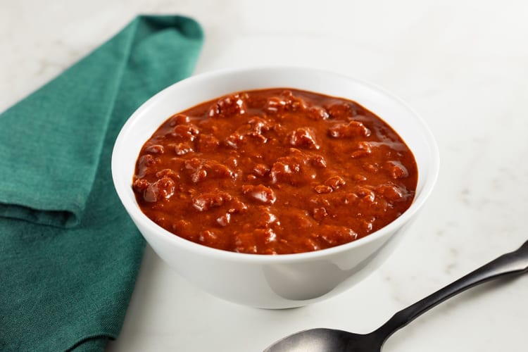 A bowl of chili next to a green napkin