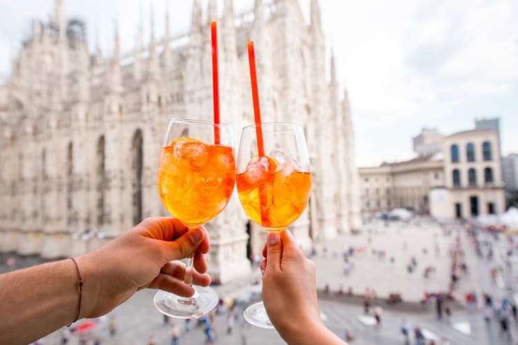 Two people cheersing Aperol spritz drinks