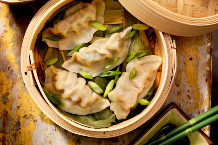 Dumplings in a bamboo steamer with chopped green onions