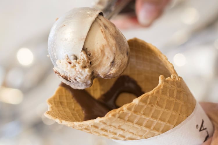 A person scooping gelato into a cone