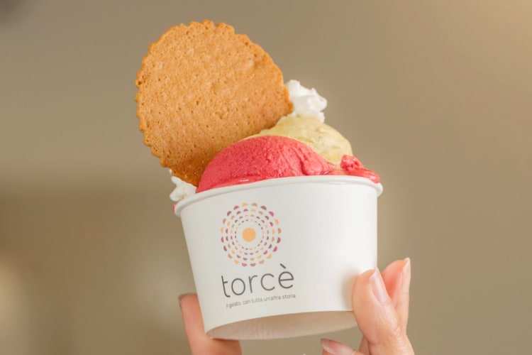 A person holding a cup with gelato and a wafer