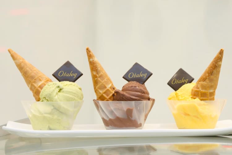 Three types of gelato topped with a cone and chocolate