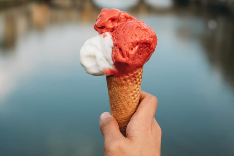 A person holding a cone with two flavors of gelato
