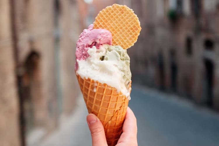 A person holding a cone with two types of gelato