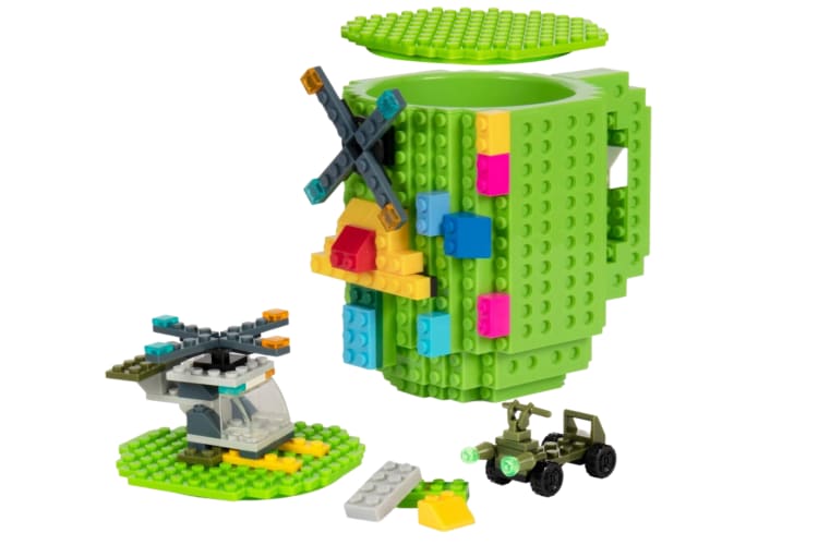 A green Lego brick mug next to other Lego pieces