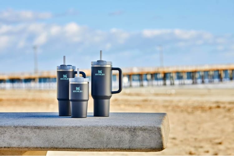 Three gray tumblers on a wall by the beach