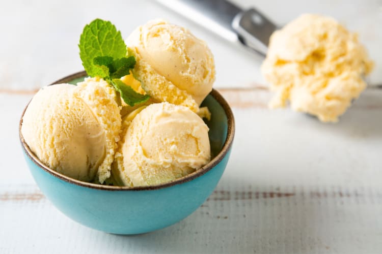 A bowl of vanilla ice cream with a sprig of mint
