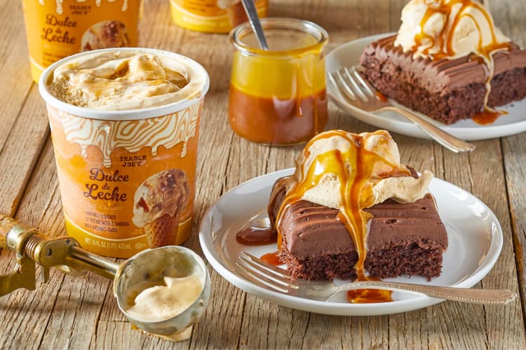 A tub of Trader Joe's ice cream next to sheet cake topped with ice cream