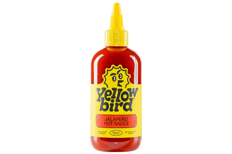A bottle of Yellowbird hot sauce with a cartoon bird logo