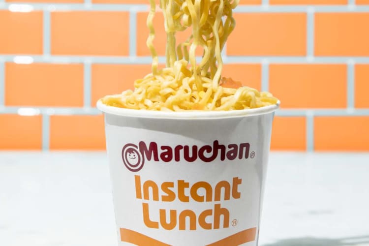 A white and orange cup with instant noodles