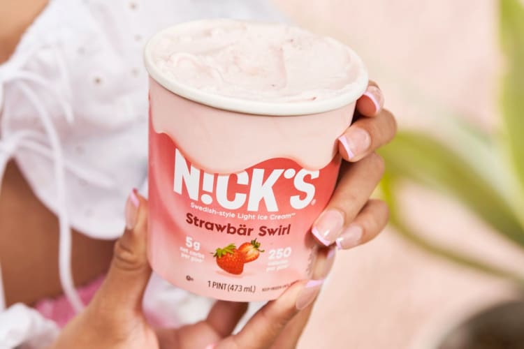 A person holding a tub of strawberry ice cream