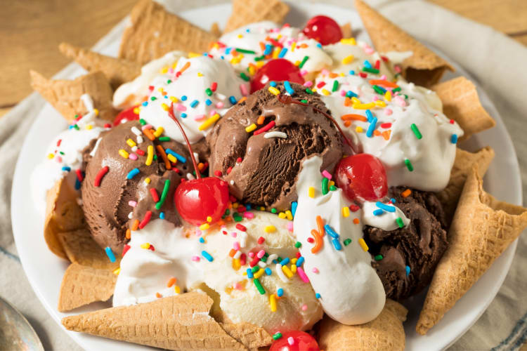 A dessert with ice cream, ice cream cones and cherries