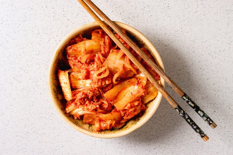 A bowl of kimchi with chopsticks