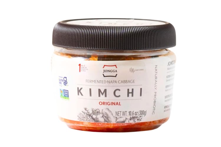 A plastic tub of kimchi with a black lid