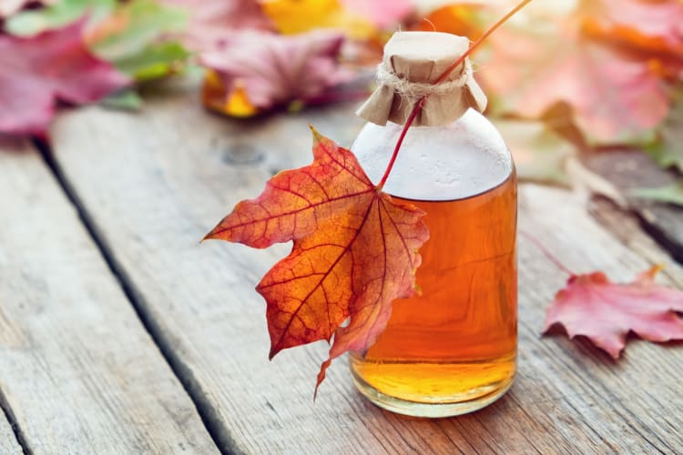 A glass bottle of maple syrup and a maple leaf