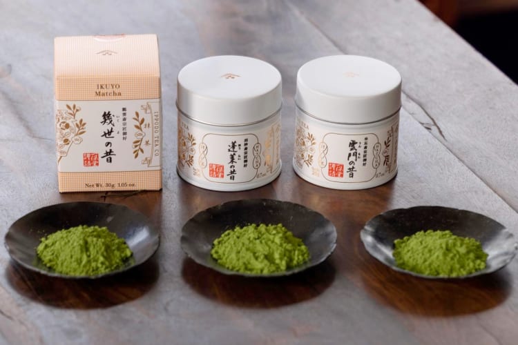 Three containers with Japanese writing next to three dishes of matcha powder