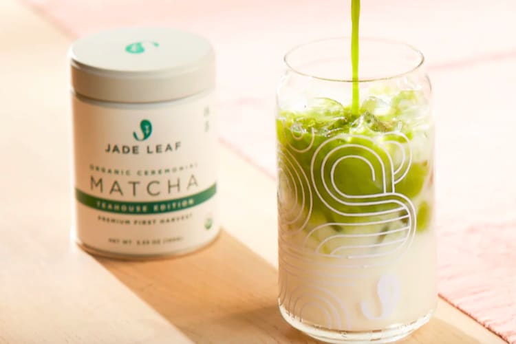 A matcha latte next to a container of matcha powder