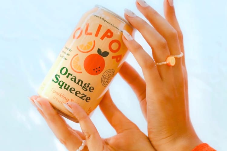A person holiding a can of orange soda