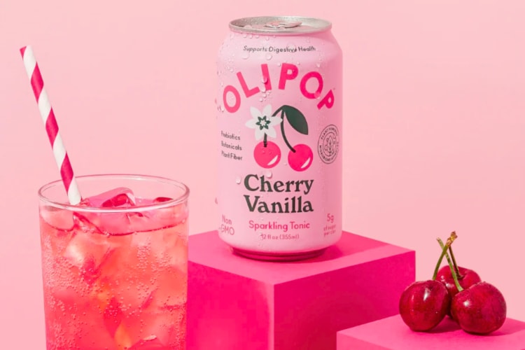 A pink can of cherry vanilla soda next to fresh cherries