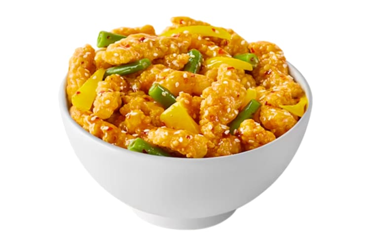 A bowl of honey and sesame chicken with green beans and yellow pepper