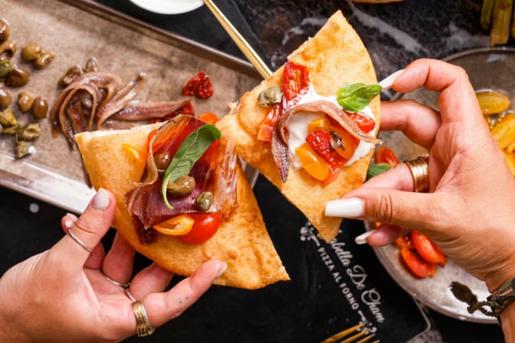 Two people holding fried pizza