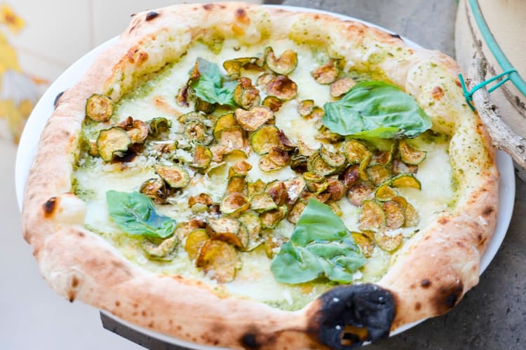 A pizza with white sauce, zucchini and basil