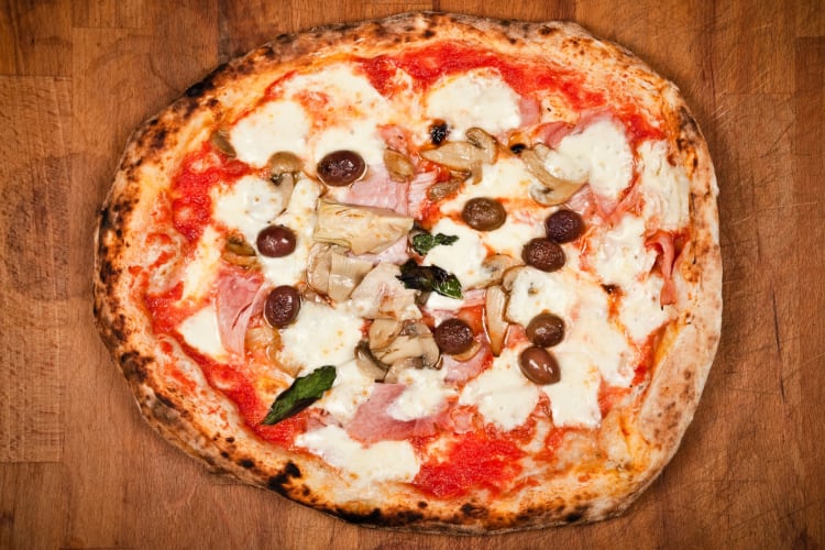 A pizza with ham, olives and mushrooms