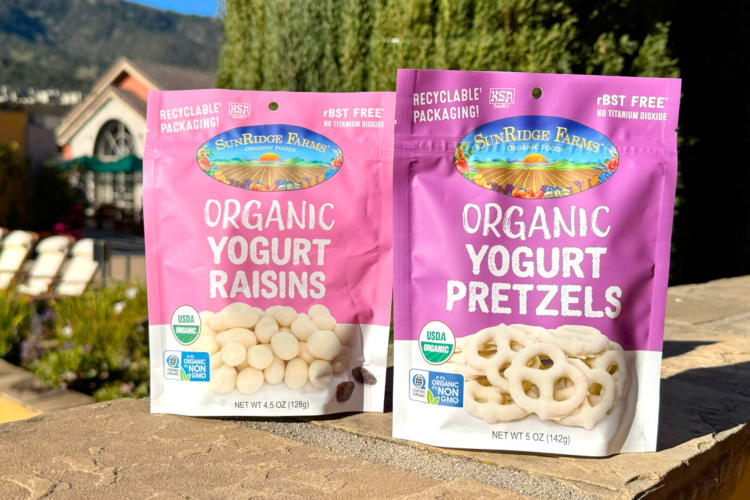 A pink bag of yogurt pretzels next to a pink bag of yogurt raisins