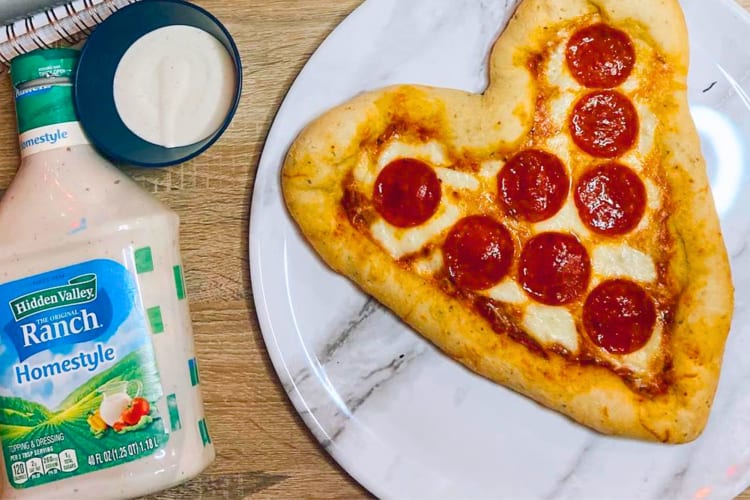 A bottle of ranch next to a heart-shaped pizza