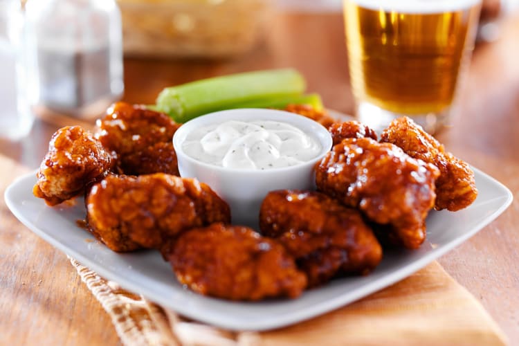 A plate of wings with a bowl of ranch dressing
