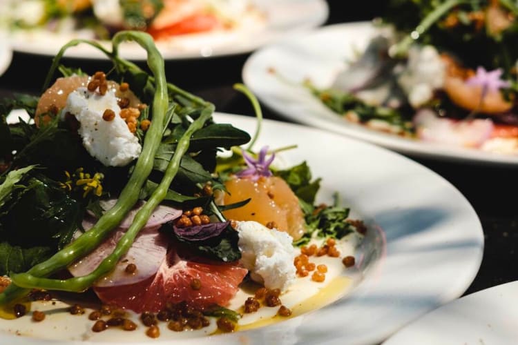 A bowl of salad with greens, goat cheese and citrus fruits