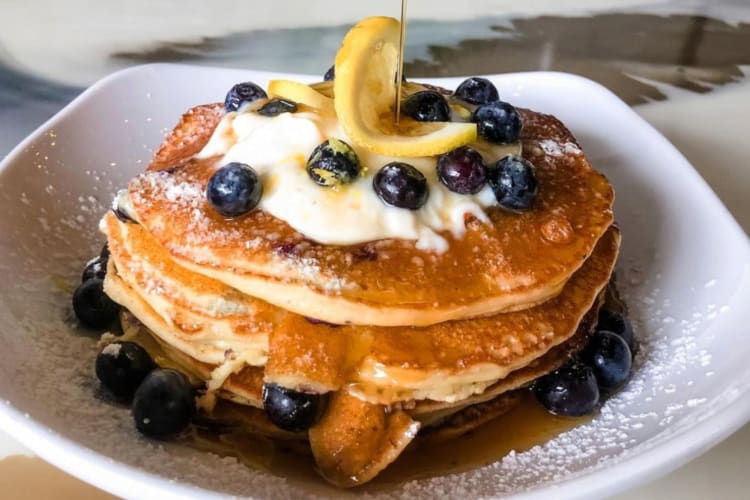 A stack of pancakes with blueberries and lemon