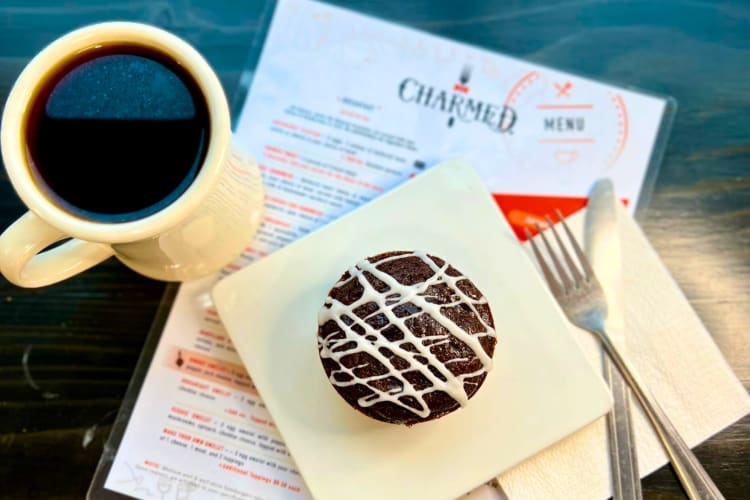 A muffin, cup of coffee and menu on a table