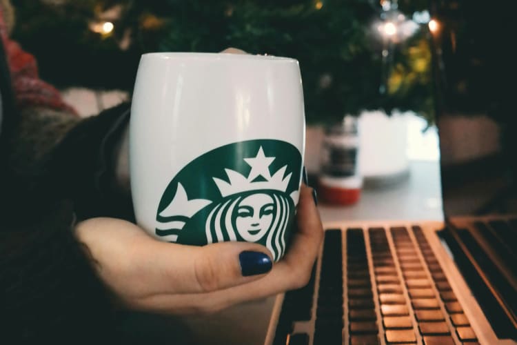 A person holding a Starbucks coffee cup