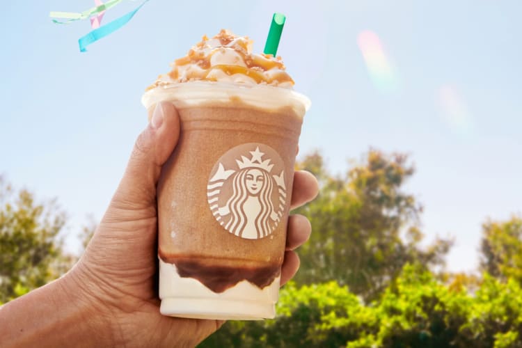 A person holding a Starbucks Caramel Ribbon Crunch Frappuccino