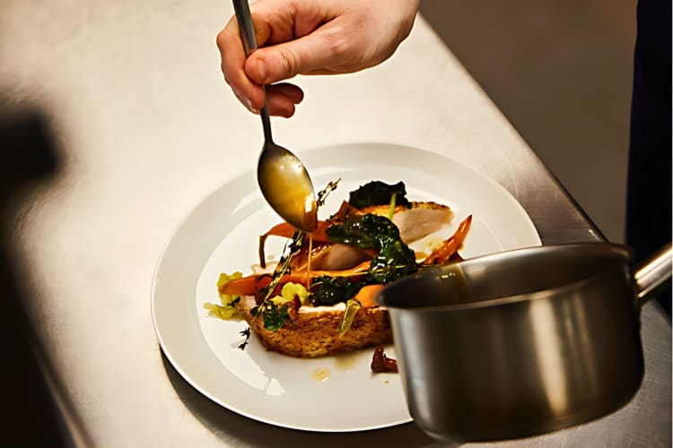 A chef adds the finishing touches to a plate of roast chicken before serving.