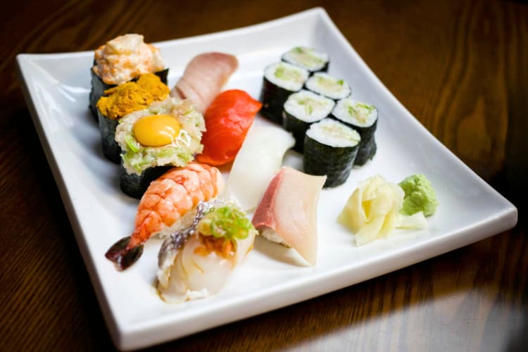 Different types of sushi, pickled ginger and wasabi on a plate