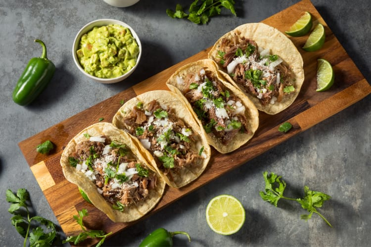 Beef tacos next to lime and guacamole