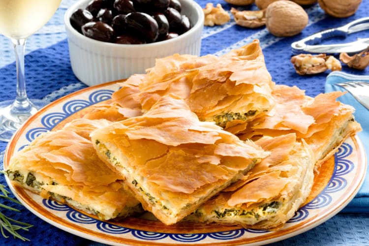 Spanakopita on a plate next to black olives