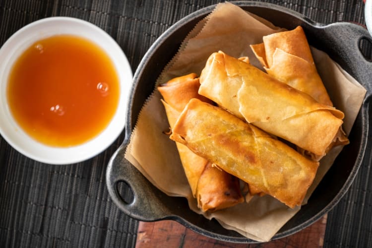 Spring rolls in a dish next to dipping sauce