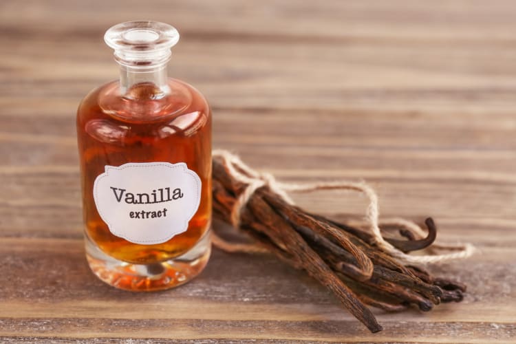 A bottle of vanilla extract next to fresh vanilla