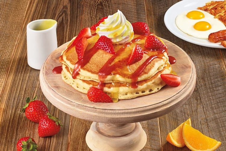 Buttermilk pancakes topped with strawberries, strawberry sauce and cream.