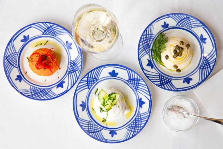 Three blue and white plates with dips and a glass of wine