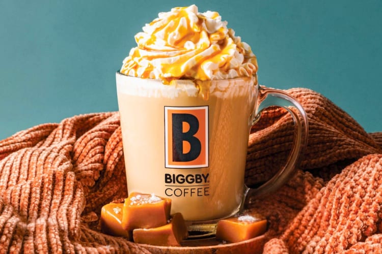 A caramel coffee drink in a Biggby Coffee glass mug