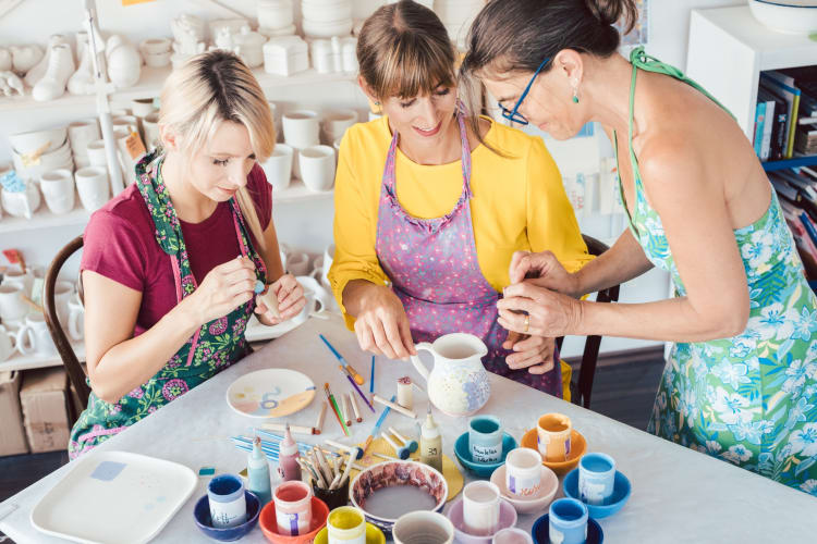 Three women in a pottery painting studio