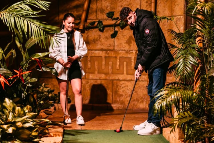 A couple playing on an indoor mini golf course