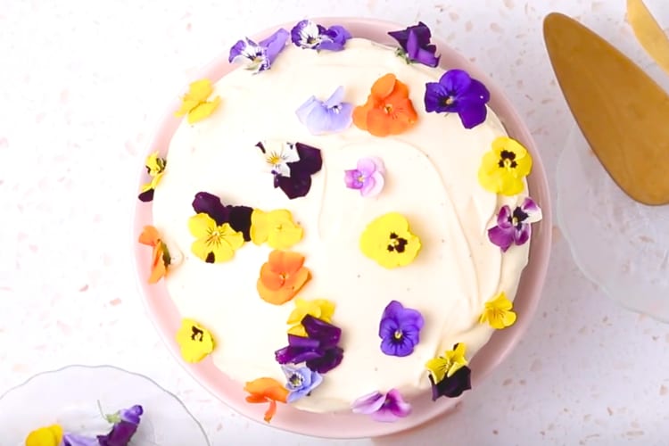 A cake with white frosting and edible flowers