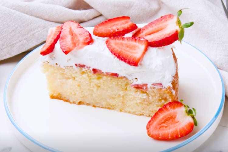 A sponge cake with white frosting and strawberries