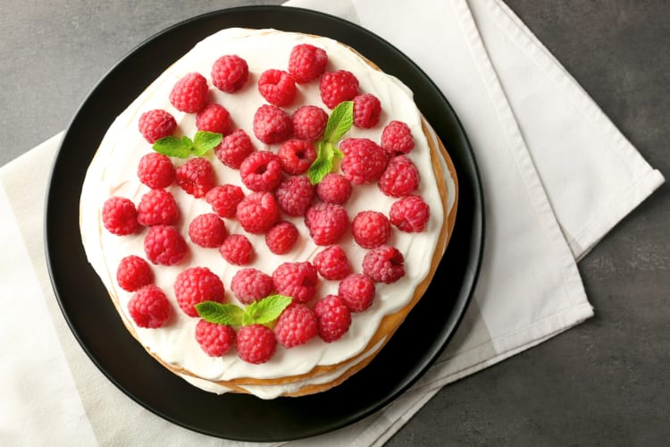 A cake with frosting and raspberries