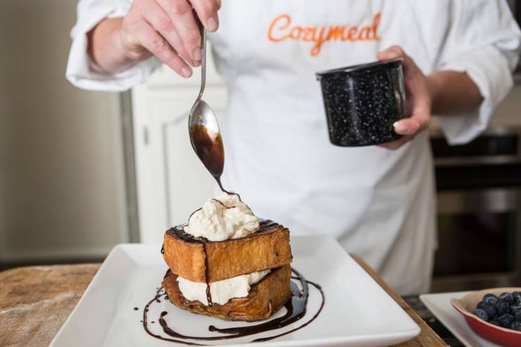A person drizzling chocolate sauce on French toast